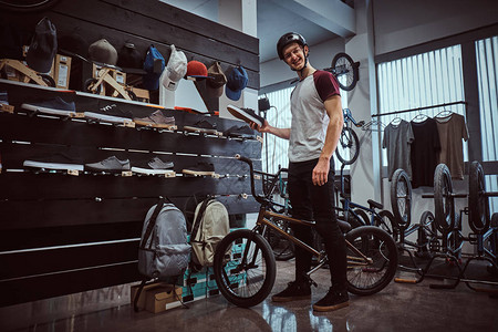快乐的年轻人站在他的自行车上在商店里选图片