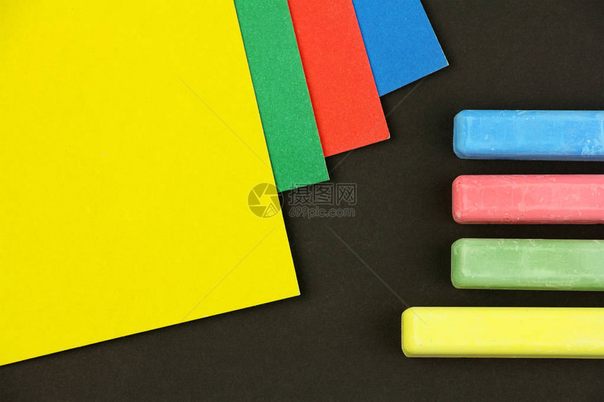 黑色背景上的四种彩色儿童蜡笔和纸学校或学前活动用不同颜色的粉笔顶视图黄色图片