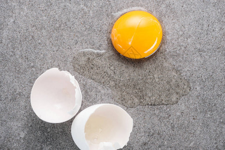 灰色背景中带蛋黄和蛋白质的生碎鸡蛋的特写图片