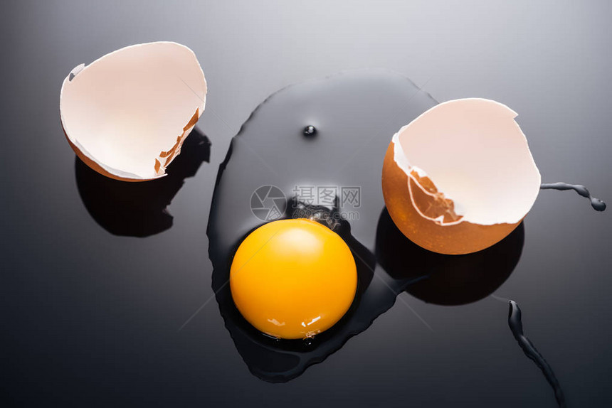 黑色背景中带有蛋黄蛋白质和蛋壳的新鲜碎鸡蛋的特写图片