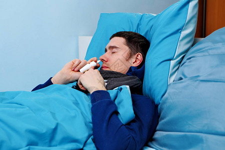 病人用鼻喷雾躺在床上时带着蓝枕头图片