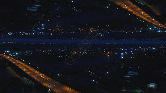 河桥的空中夜景与移动的汽车和城市的夜灯图片