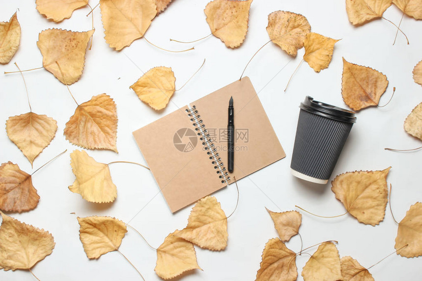 笔记本和咖啡杯在白背景上有落叶新闻概图片
