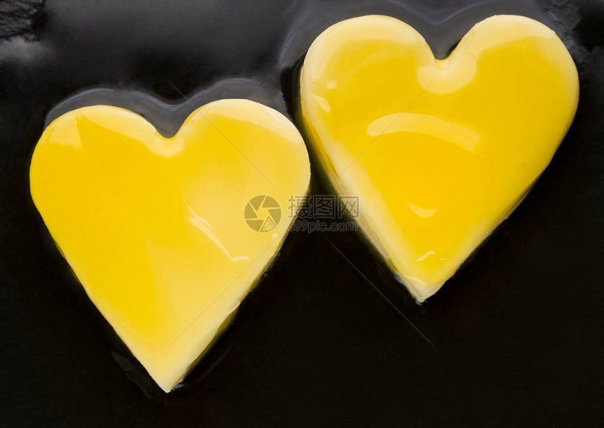 两块心形黄油在黑锅上熔化图片