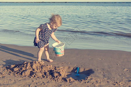 可爱的小女孩在沙滩上玩耍探索和探索在海图片