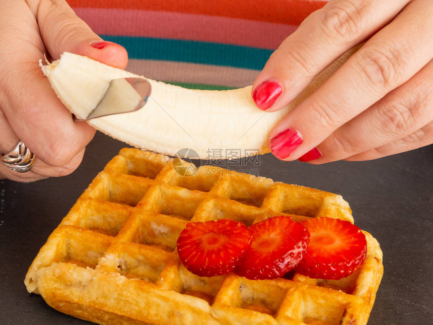 一个红指甲的女人切草莓和香蕉然后放在比利时的华图片