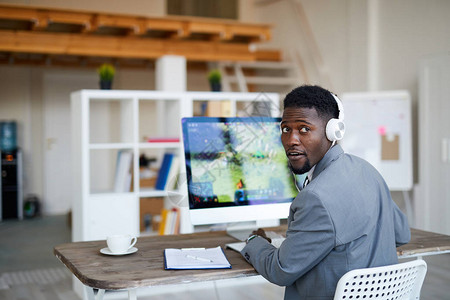 身穿正装和耳机的非洲美洲青年编辑在坐电脑监视器图片