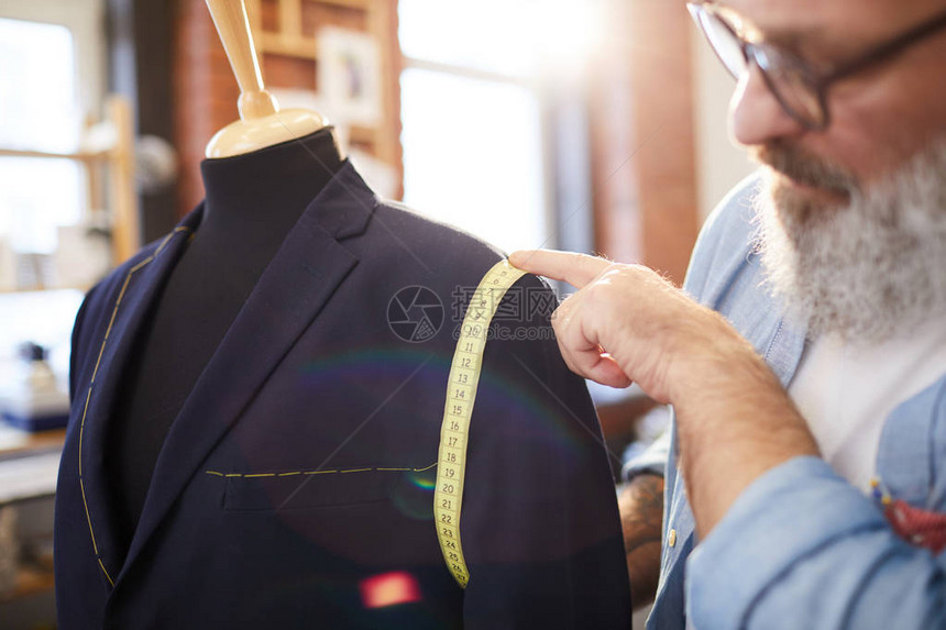 在为客户之一缝新西装时测量假冒外衣袖图片