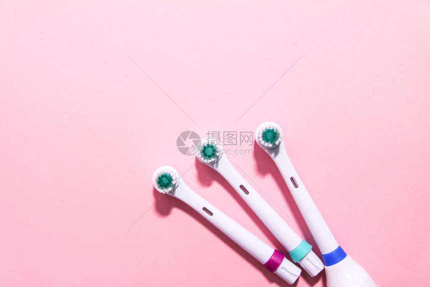 柔和的浅粉色背景上的两把电动牙刷图片