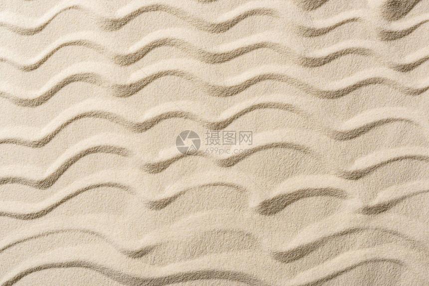 带沙子和平滑波浪的纹理背景的顶视图图片