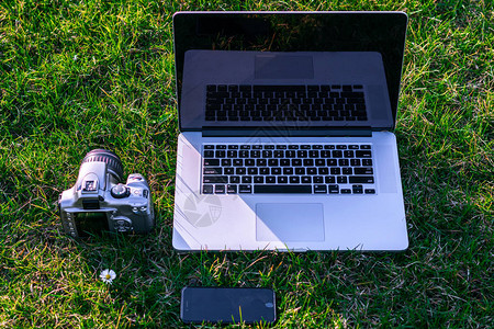 用智能手机和Dslr相机拍摄绿色草地的笔记本电图片