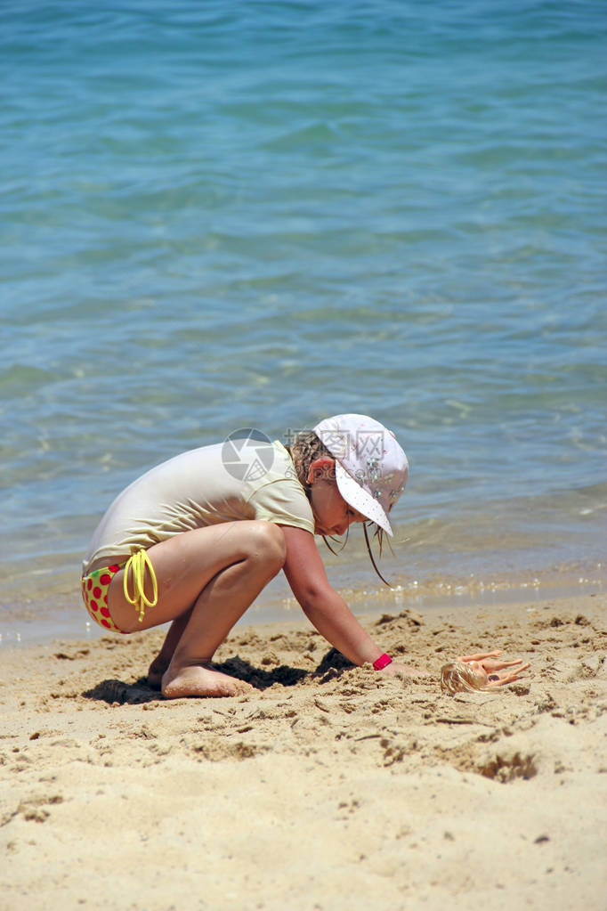 小女孩在沙滩上玩沙子暑假期间在海边沙滩上玩耍的女图片