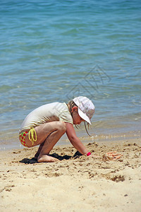小女孩在沙滩上玩沙子暑假期间在海边沙滩上玩耍的女图片