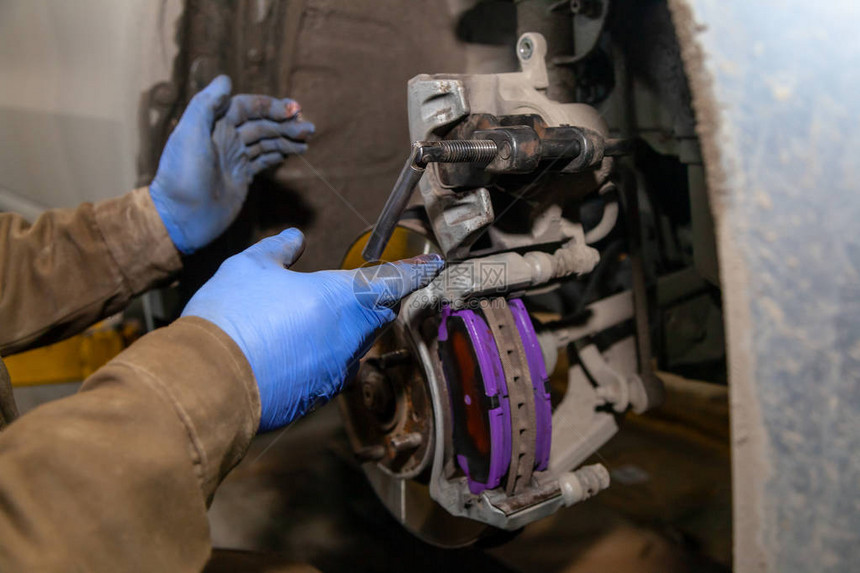 关闭专业汽车修理工在汽车维修服务中更换前刹车片汽车工人在维修服务站车图片
