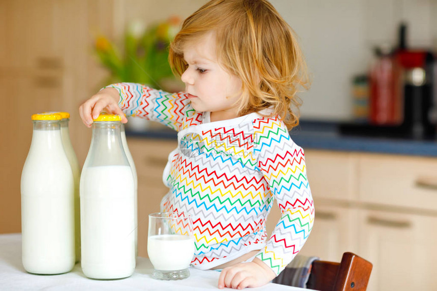 可爱的蹒跚学步的女孩早餐喝牛奶图片