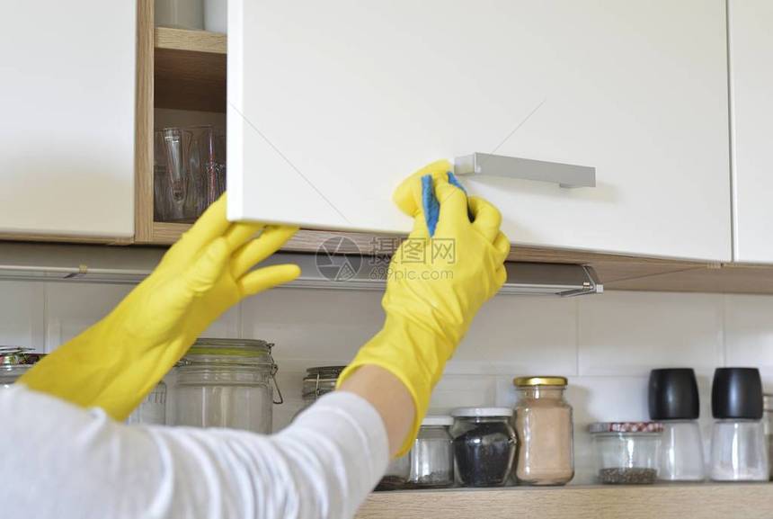 妇女戴黄色手套在厨图片