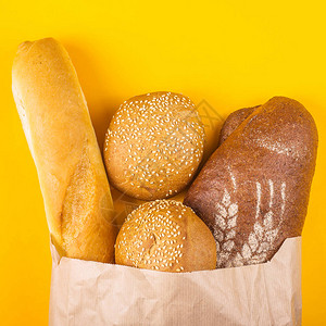 黄色背景的纸袋中新鲜多样的面包图片