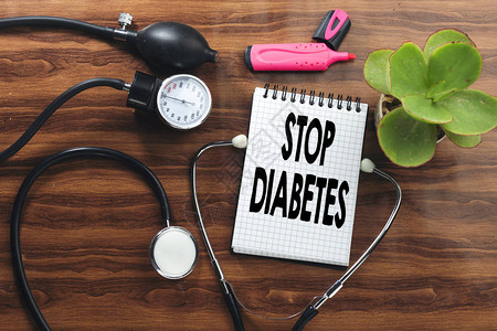 停止在白笔记本和黑色听诊器木板上的血压计上写糖尿图片