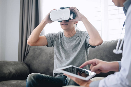 年轻的亚洲男病人使用虚拟现实眼镜看技术来检查身体病人图片