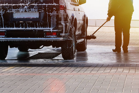 男人在晴朗的晴天用刷子洗他的黑色汽车在自助洗车场用肥皂水清洗柔图片
