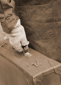 旅行期间戴皮手提箱和破手套的男子背景图片