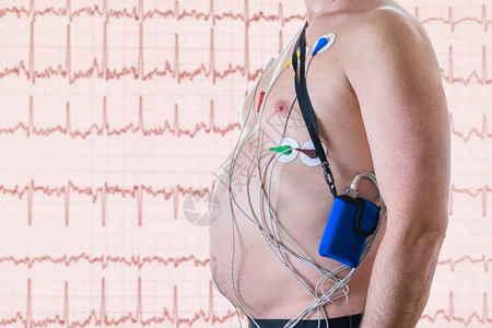 一名男子在带有心电图的红色屏幕背景下接受心脏检查吊带的方法心脏图片