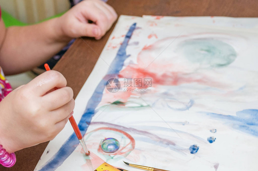 一个小女孩在幼稚园用油漆和刷子画出一张明图片