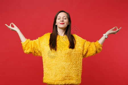 穿着黄色毛皮衫闭着眼睛的放松的年轻女子握住瑜伽手势图片