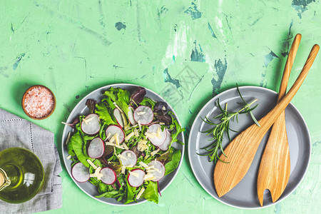 沙拉配萝卜橄榄油粉红盐空陶瓷碗绿色混凝土混凝土纹理背景上的沙拉木勺图片