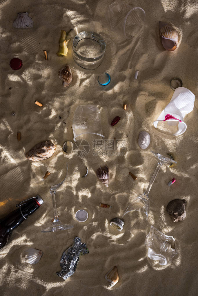 贝壳玻璃瓶散落的烟头碎玻璃苹果核塑料杯和糖果包装纸的顶视图图片