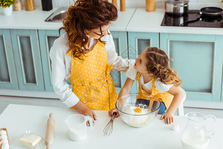 穿着围裙的母亲和女儿在厨房一起做饭时图片