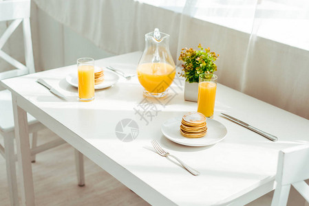 白桌上早餐供应的甜薄煎饼和新鲜橙汁图片