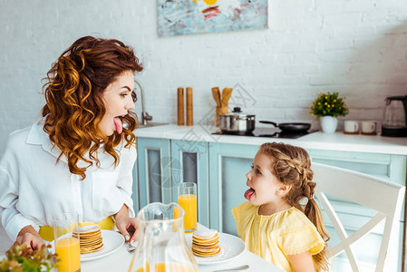 女儿和母亲在吃早餐时吐出舌头图片