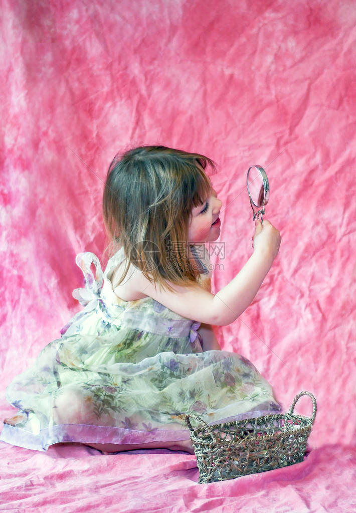 美丽的小女孩看着镜子的反光和她的化妆品图片