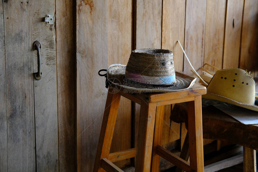 乡村间别墅木凳上的柳条藤帽图片