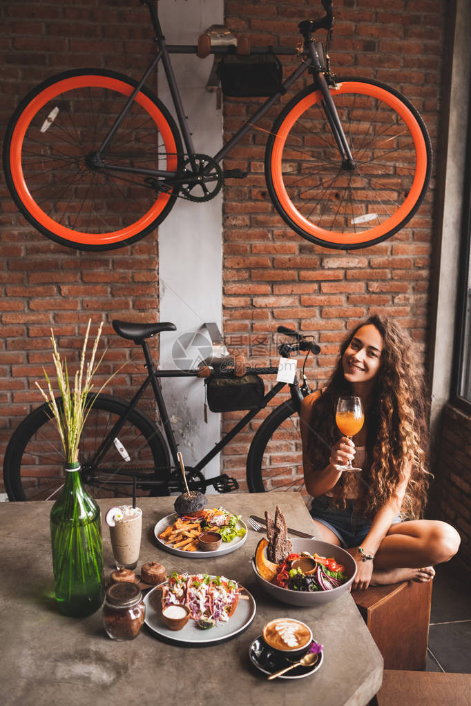 妇女享受新鲜有机素食品和在带有自行车设计的时装式咖啡厅中图片