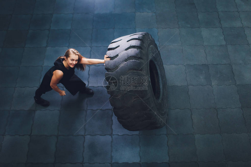 在健身房里转身和搬运女运动员用大轮胎锻炼的图片