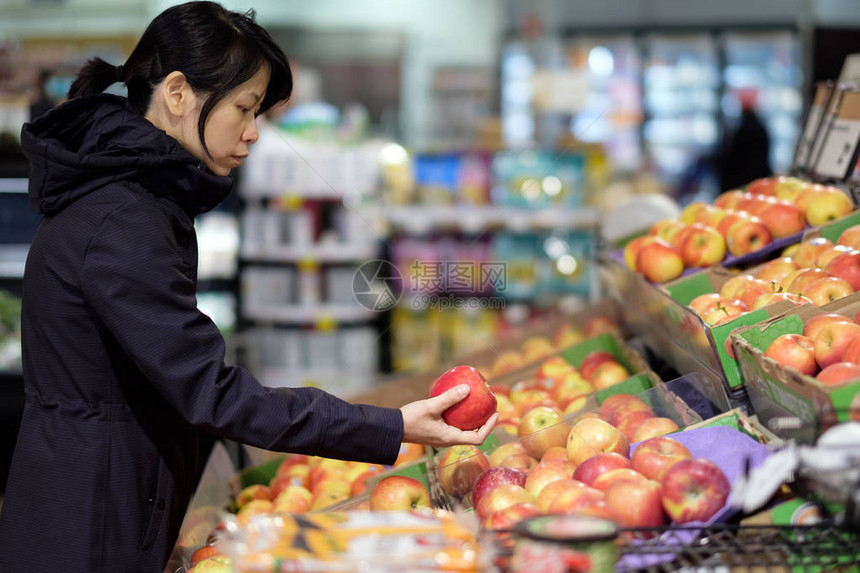 亚洲女在杂货店购买持有和选择新鲜苹果图片