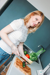 金发成年妇女在家里厨房做菜的图片