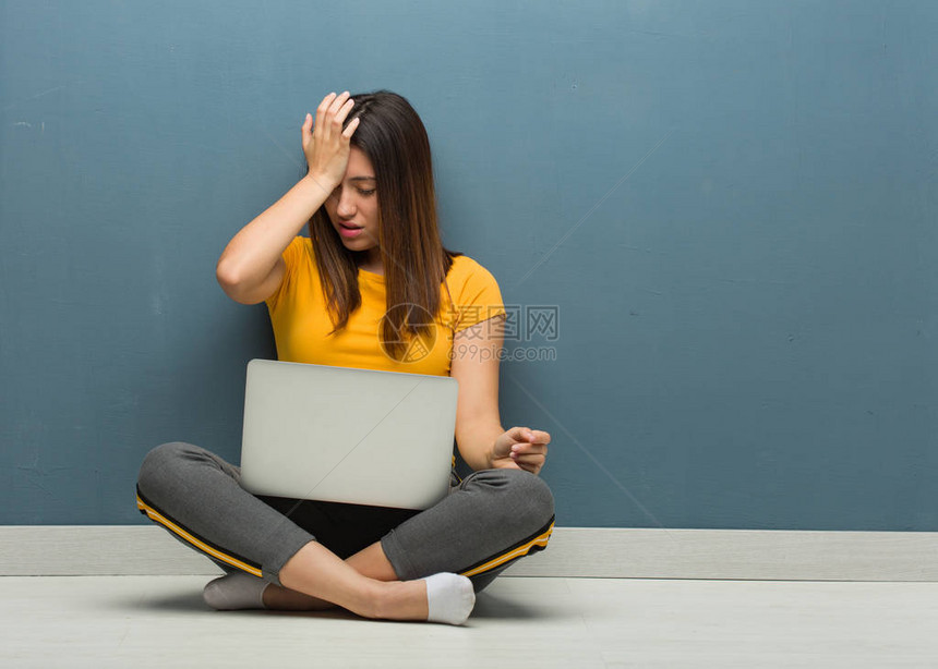 年轻女士坐在地板上拿着笔记本电脑的健忘图片