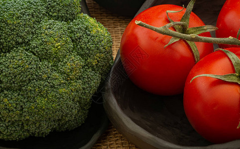 有机蔬菜番茄西红柿花椰菜黑土碗和用黄麻布桌进行的奶黑粘土巡图片