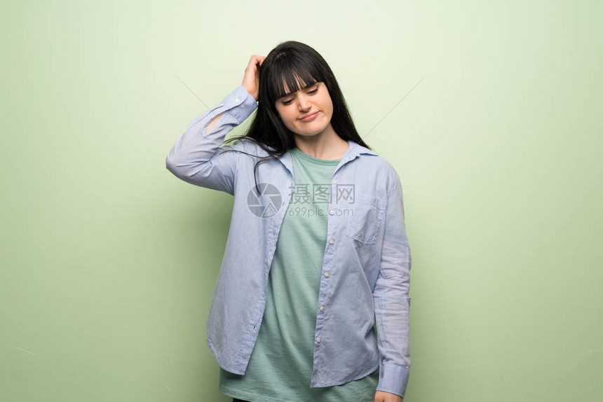 绿墙上的年轻女子挠头时有疑问图片