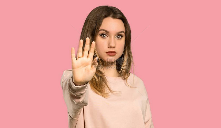 带着粉红色毛衣的少女停止手势否认一种对与世隔绝的粉红背景图片
