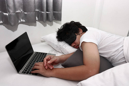 厌倦了过度劳累的亚洲男人用笔记本电脑睡图片