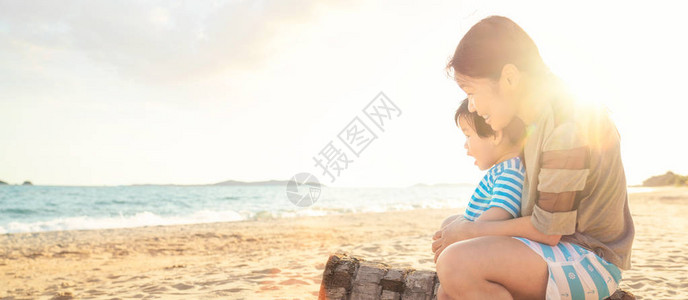 母亲和儿子一起坐在沙滩上图片