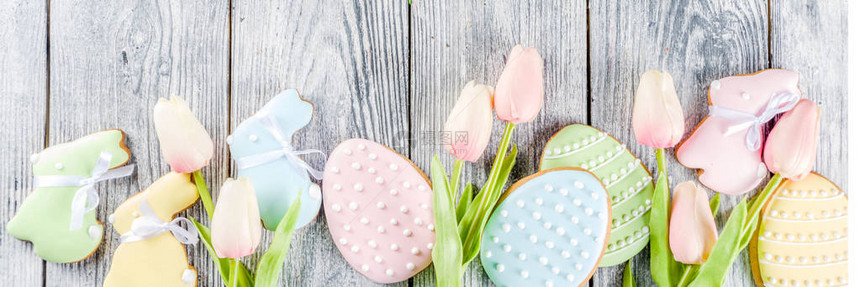 复活节贺卡背景与柔和的彩色鸡蛋和自制饼干形状的鸡蛋和带篮子郁金香质朴的木桌复制空图片