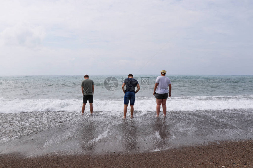 三个最好的朋友去海边年轻人去试水温男人们站在海边图片