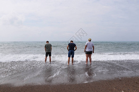 三个最好的朋友去海边年轻人去试水温男人们站在海边背景图片