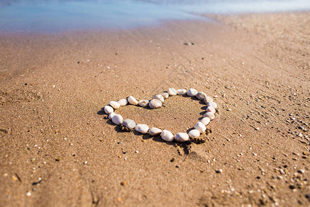 沙子上的鹅卵石之心爱的宣言情人节海水和沙子在沙滩上放松由石头制图片