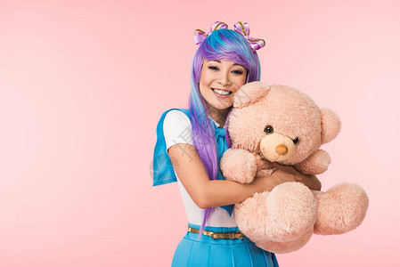 动漫拥抱美图带着泰迪熊的假发微笑着的亚洲动漫女孩在粉背景